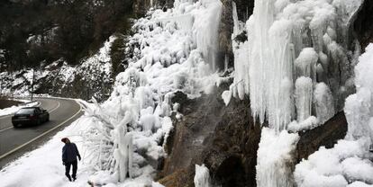 Un hombre observa junto a la N-137, en Urzainqui (Navarra), las formaciones de hielo originadas en las paredes de la montaña.