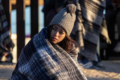 Colombian migrant Gisele, 18, bundles up against the cold after spending the night camped alongside the US-Mexico border fence on December 22, 2022 in El Paso, Texas. 