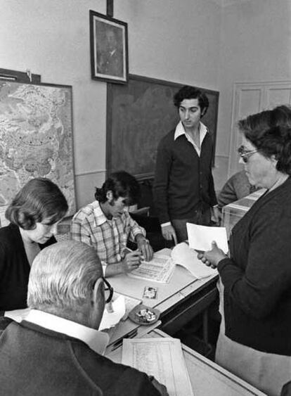 Una mujer acude a depositar su voto en una mesa situada bajo un retrato de Franco y un crucifijo.