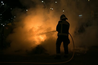 Un bombero intenta apagar uno de los contenedores incendiados durante una manifestación en apoyo a Pablo Hasél, en Barcelona