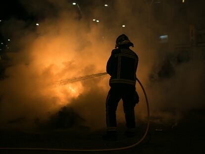Un bombero intenta apagar uno de los contenedores incendiados durante una manifestación en apoyo a Pablo Hasél, en Barcelona