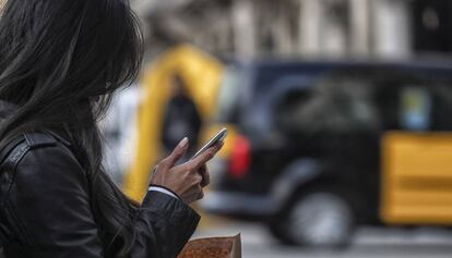 Una mujer consulta su teléfono móvil en el paseo de Gràcia.