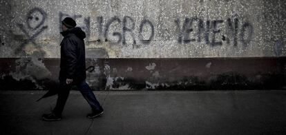 Un vecino pasa ante una pintada contra el lindano en las viviendas sociales de Torneiros (O Porriño).