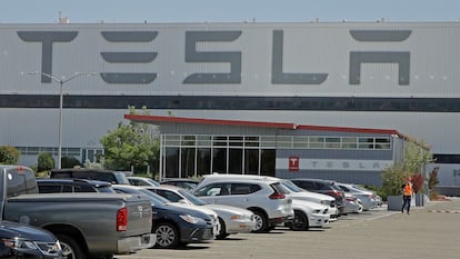 A man walks in the Tesla plant parking lot