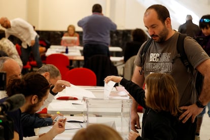 Una niña ayuda a un votante a introducir su voto en la urna en un colegio electoral de Portugalete, este domingo. 