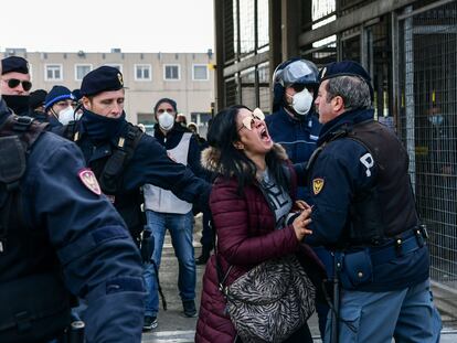 Agentes de policía sujetan a la pariente de un recluso que protesta ante una cárcel en Módena (Italia).