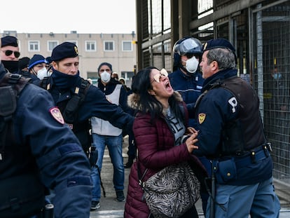 Agentes de policía sujetan a la pariente de un recluso que protesta ante una cárcel en Módena (Italia).