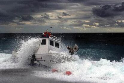 Las olas rompen contra la embarcación que ayer naufragó en la costa de Almería, y que poco después encalló en la playa. Tres de los tripulantes murieron y un cuarto pescador pudo agarrarse a una boya y sobrevivir.