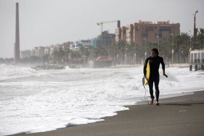 Un surfista corre por la playa de Huelin en la capital malagueña mirando el fuerte oleaje debido al temporal de Levante que está azotando estos días las costas del litoral de Málaga. 