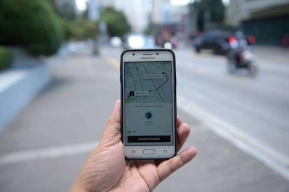 Un hombre sostiene un tel&eacute;fono con la aplicaci&oacute;n Uber