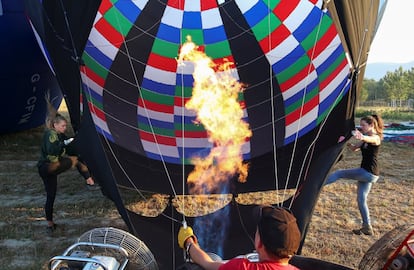 Varias personas trabajan para levantar del suelo un globo aerostático durante un festival en Todi (Italia).