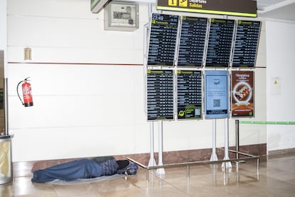 Una persona duerme en los pasillos que conectan la terminal 1 y 2 de Barajas durante la madrugada del lunes. 