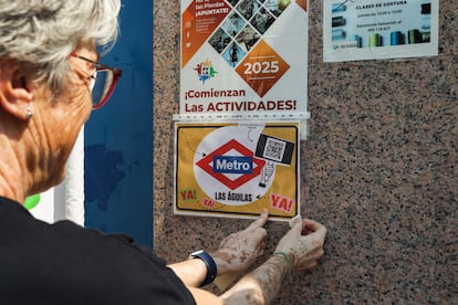 Una vecina colgando un cartel que exige a la Comunidad de Madrid una boca de metro en el barrio de Las Águilas.