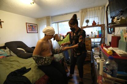 Sandra recibe ayuda de su amiga Gina Ramírez tres meses después de que se le practicara una mastectomía bilateral.