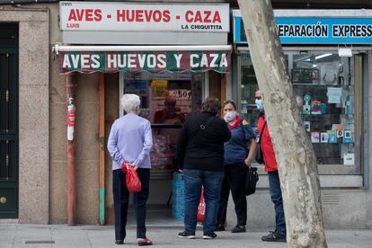 Varios vecinos conversan frente a un comercio en García Noblejas.