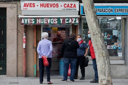 Varios vecinos conversan frente a un comercio en García Noblejas.