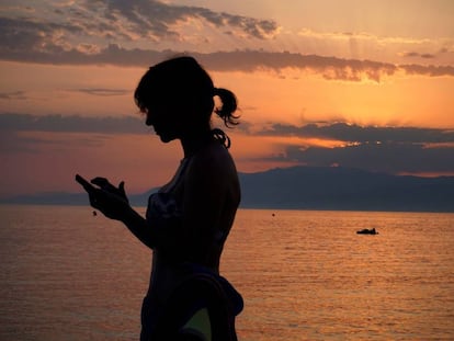 Una mujer revisa su teléfono móvil en la playa de Cabo de Gata, en Almería.