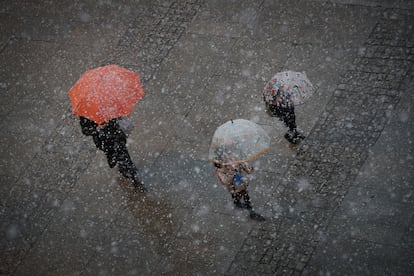 Dos niños se dirigen con su madre al colegio el viernes, cruzando la plaza del Castillo de Pamplona bajo una intensa nevada.