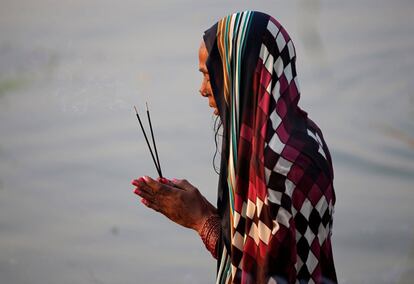 Una mujer hindú reza al dios Sol en aguas del río Sabarmati, durante el festival religioso Chhath Puja, en Ahmedabad (India), el 13 de noviembre de 2018.