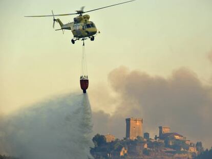 Un helicóptero descarga agua con el castillo de Monterrei al fondo