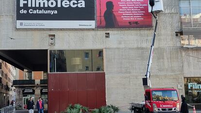 Una grúa cuelga el cartel de los 10 años de la Filmoteca en el Raval.