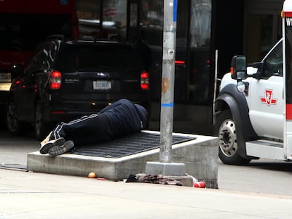 Una persona sin hogar duerme este martes en la salida del Hospital General de Toronto, en Canadá.