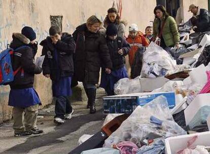 Niños que van al colegio con sus madres pasan junto a montañas de basura ayer en un barrio de Nápoles.
