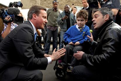 El candidato conservador, David Cameron (izquierda), discute con Jonathan Bardley, padre de un niño discapacitado.