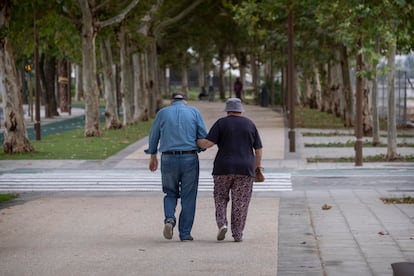 Dos personas mayores caminan por la calle tomadas del brazo.