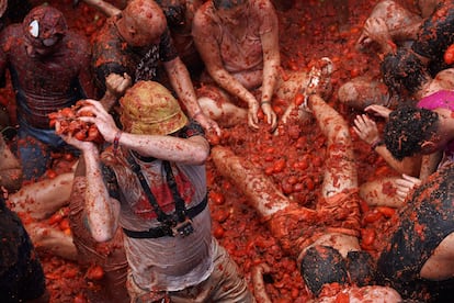 Varias personas cubiertas de tomate participan en la festividad de la Tomatina, este miércoles.