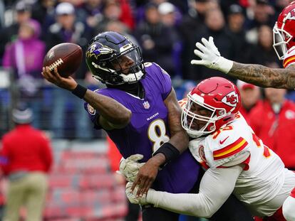 Ravens Lamar Jackson se apresura a pasar mientras evita un saco por parte del equipo defensivo de los Kansas City Chiefs, Chris Jones.