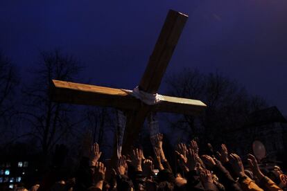 Um grupo de pessoas levanta as mãos para alcançar uma cruz no centro de Kiev, Ucrânia, em 24 de fevereiro de 2014.