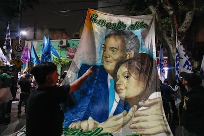 Seguidores de Massa llevan una bandera de Néstor Kirchner y Cristina Fernández durante los festejos luego de la primera vuelta.