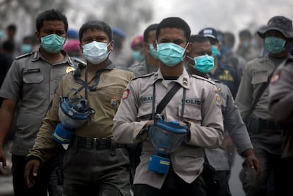 Miembros de los equipos de rescate y policías caminan con mascarilla por la aldea de Kinaredjo, afectado por la errupción del volcán Merapi.