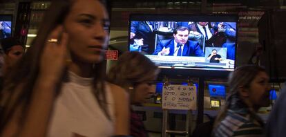 Pessoas passam diante de TV durante vota&ccedil;&atilde;o na C&acirc;mara, nesta quarta.