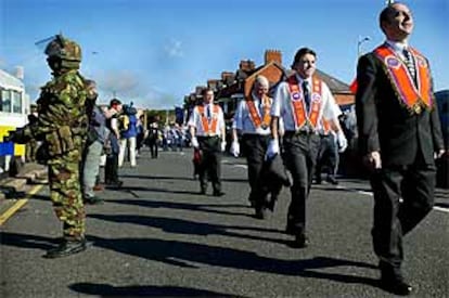 Un desfile de la Orden de Orange pasa junto a soldados británicos en Belfast.