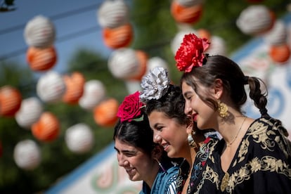 Tres chicas vestidas de flamenca con flores cabeza.