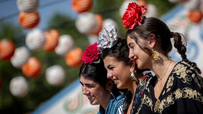 Tres chicas vestidas de flamenca con flores cabeza.