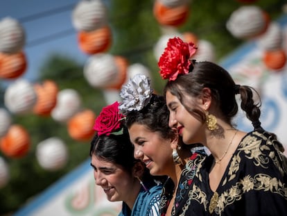 Tres chicas vestidas de flamenca con flores cabeza.