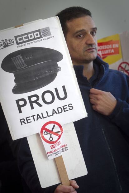 Un <i>mosso</i> sostiene una pancarta con la leyenda "basta de recortes" en la comisaría de la plaza de Espanya, en Barcelona.