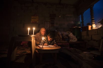Una palestina ayuda a su hijo a estudiar, a la luz de las velas, en el campo de refugiados de Jan Yunis (Gaza), el pasado 19 de abril.