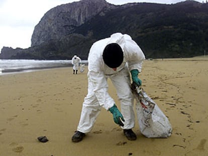 Un operario recoge chapapote en la playa vizcaína de Laga.