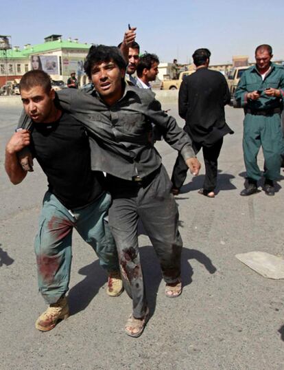 Un policía ayuda a un hombre herido durante el atentado de hoy en Kabul.