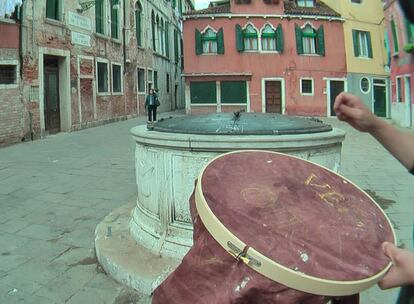 Una <i>performer</i> borda narcomensajes con hilo de oro sobre tela ensangrentada en Venecia.