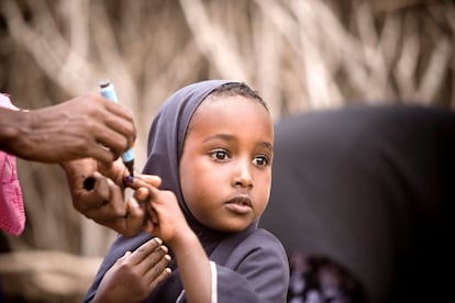 Un trabajador sanitario pintaba el dedo a una niña que acaba de ser vacunada durante una campaña contra el sarampión y la polio en Hagadera, uno de los tres principales campos de refugiados cerca de la ciudad de Dadaab, en el noreste de Kenia, en 2011. Los refugiados, que escapaban de la inestabilidad y la sequía en Somalia, eran particularmente vulnerables a enfermedades al llegar debilitados y no haber sido vacunados antes.