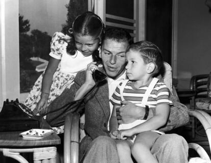 Frank Sinatra habla por teléfono junto a sus hijos, Nancy y Frank Jr., en Los Ángeles (EE UU) en 1948.