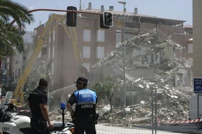 Dos policías observan las labores de derribo de un edificio en el barrio de La Viña de Lorca