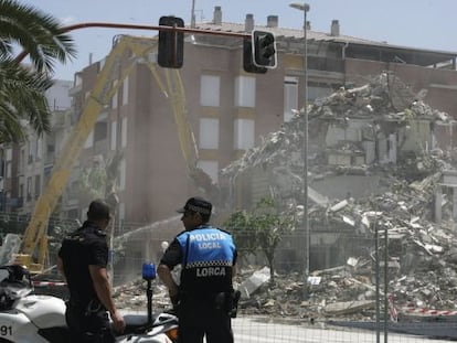 Dos policías observan las labores de derribo de un edificio en el barrio de La Viña de Lorca