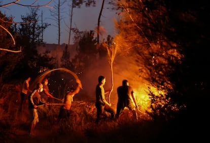 Vecinos de Vilar de Condes (Ourense) intentaban el viernes extinguir las llamas de un incendio forestal.