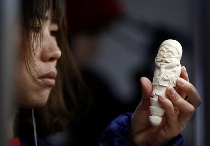 Una mujer comprueba la talla sobre de un figura de marfil en un taller en Pekín (China).